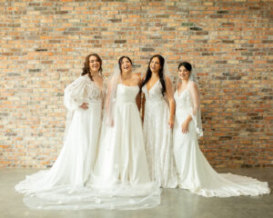 four brides modeling white wedding dresses. 