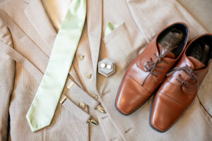 A beige tuxedo with pearl cufflinks and brown wedding dress shoes.