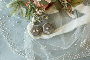 A pearl necklace and earrings set resting on a lace bridal veil.