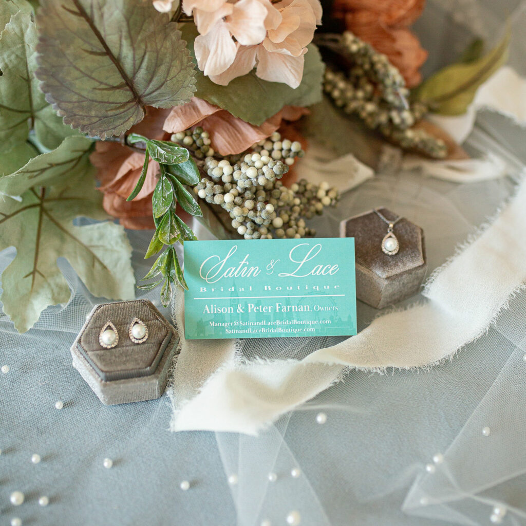 Bridal garter with blue ribbon and pearl bridal jewelry laying around it from Satin & Lace.