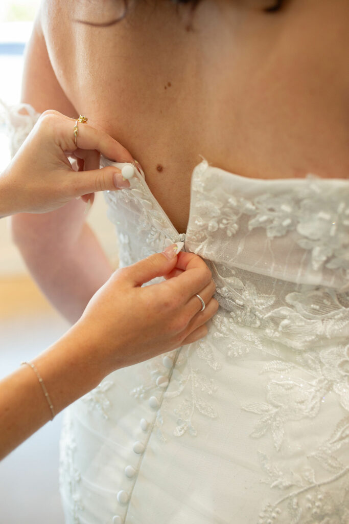 A bride trying on the Ava dress, an ivory fit and flare dress with a ruche butt and a lace train.