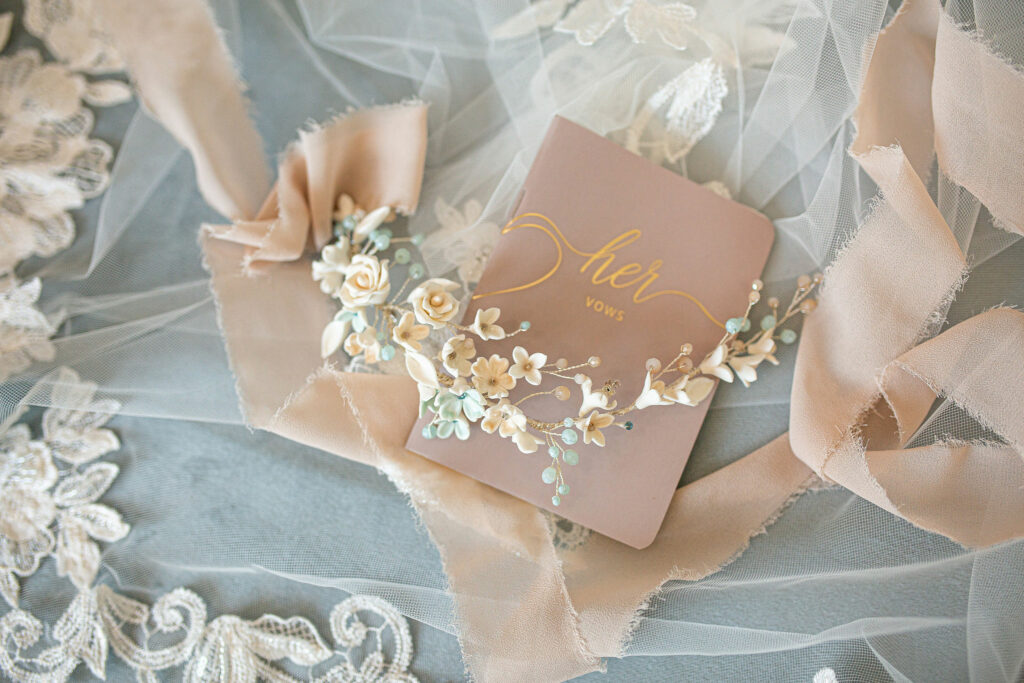 Stunning wedding headpiece with flowers laying on top of a "Her Vows" book.