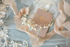 Stunning wedding headpiece with flowers laying on top of a "Her Vows" book.