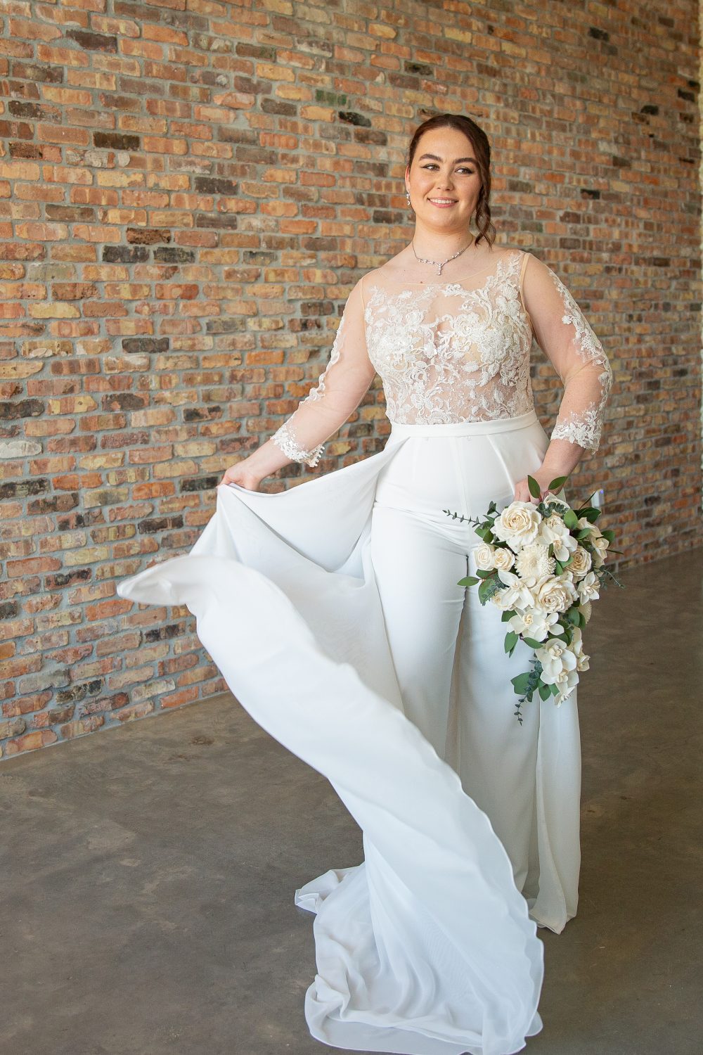 Tall bride in Selena pantsuit with detachable skirt, showcasing sheer beaded appliqués and movement, captured at Satin & Lace Bridal Boutique in Riverview, FL.