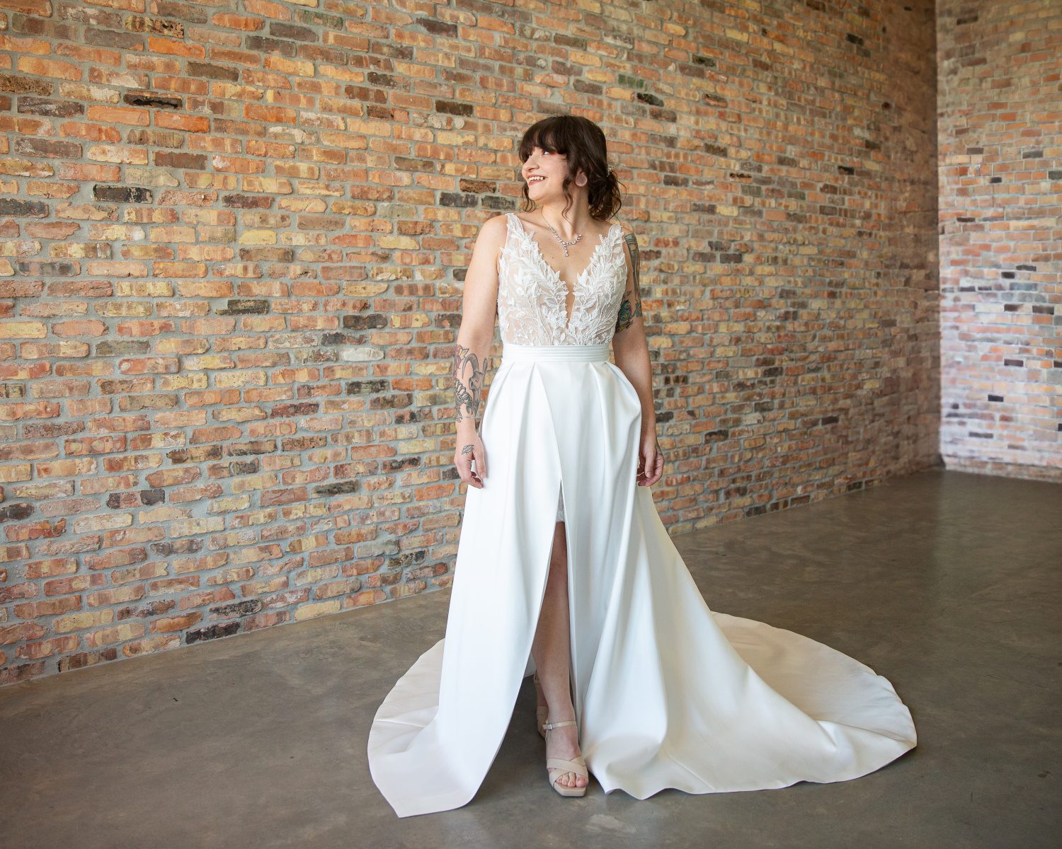 Tattooed bride wearing the Sandie wedding dress from the London Bridal Boutique, featuring a beaded appliqué mini dress with a satin overskirt. Two looks in one, showcasing the front view of the overskirt.