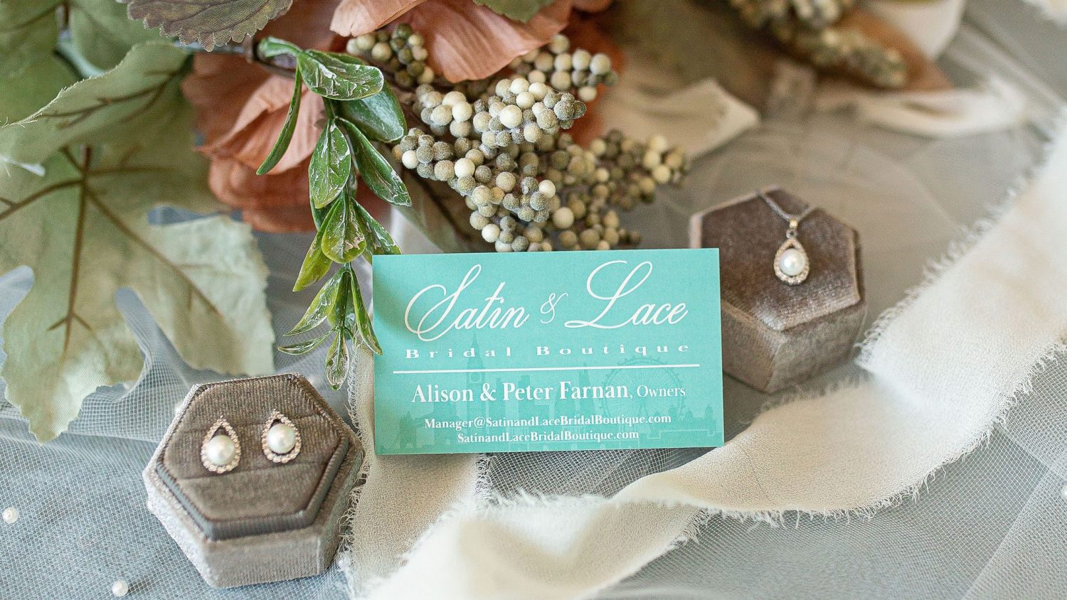 Bridal garter with blue ribbon and pearl bridal jewelry laying around it from Satin & Lace.